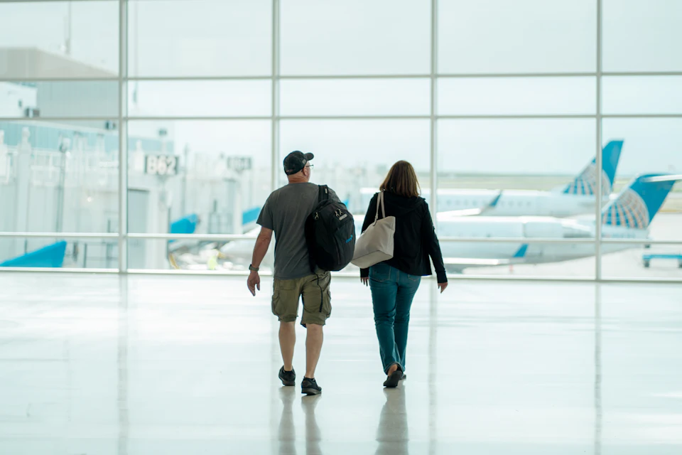 Couple walking through an airport arrivals hall with their luggage, as travellers do after landing at Marrakech Menara Airport.