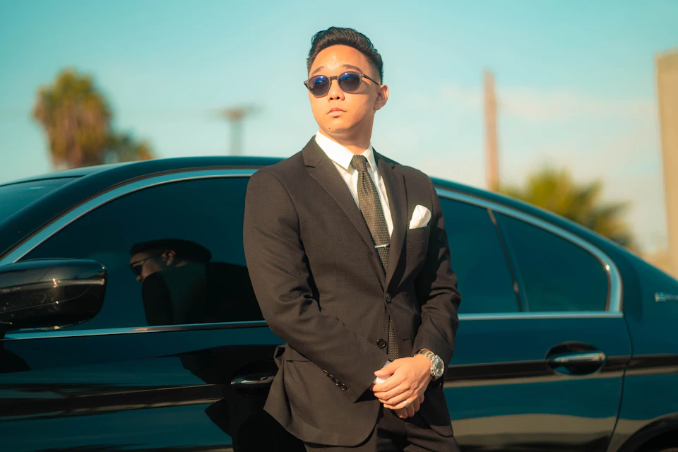 Professional driver in a suit waiting beside a private transfer car