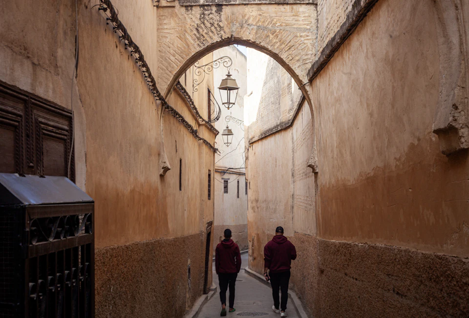 Narrow arched alley in the Fes medina, the kind of lane that leads on foot from the gate to a riad