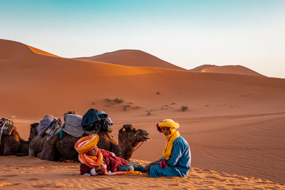Travellers resting on the orange Erg Chebbi dunes at Merzouga, the end point of the long drive from Marrakech