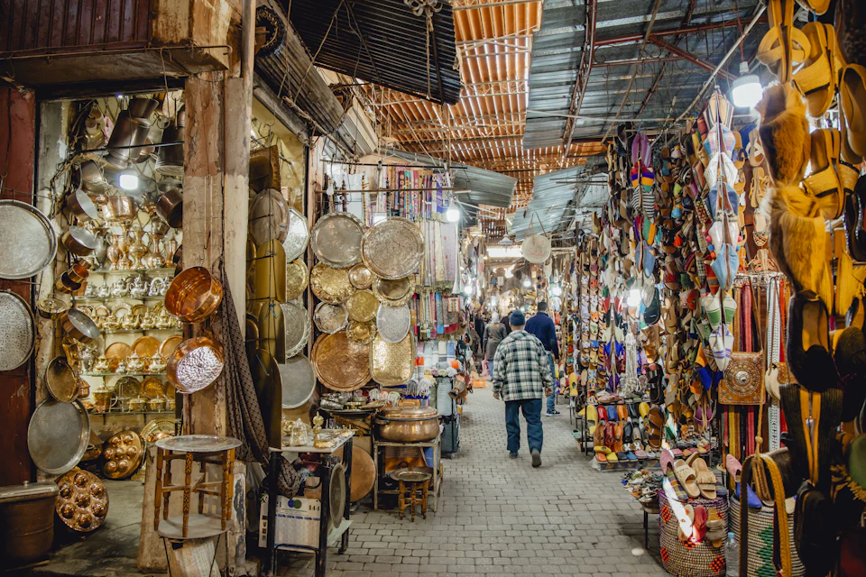 Busy souk lane in Marrakech with stalls and shoppers, a place where you pay in dirham cash and not by card