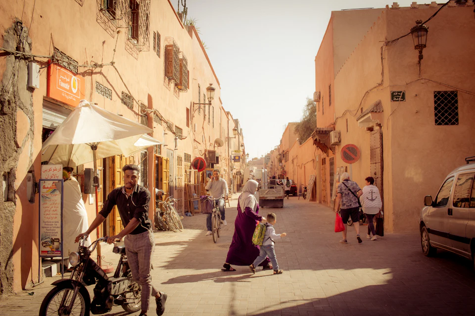 Street scene in a Moroccan city with cars and pedestrians, where travellers choose between taxis and ride apps